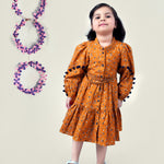 A girl wearing mustard color printed cotton frock with belt