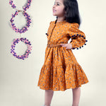 A girl wearing mustard color printed cotton frock with belt