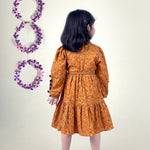 A girl wearing mustard color printed cotton frock with belt
