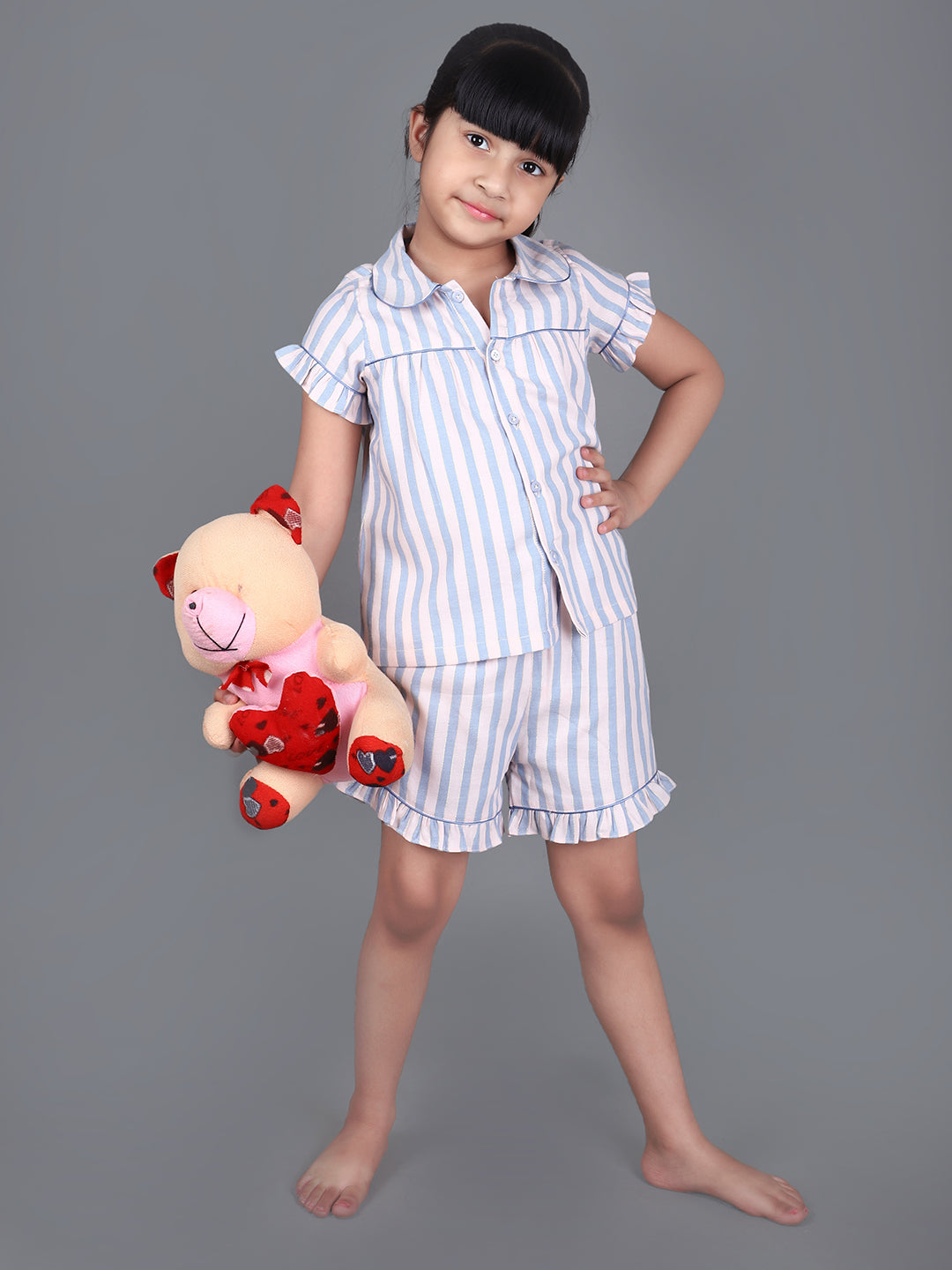 A girl wearing Blue striped cotton night dress with shorts and holding a doll
