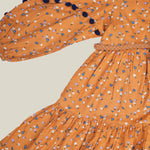 A girl wearing mustard color printed cotton frock with belt