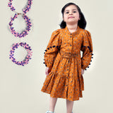 A girl wearing mustard color printed cotton frock with belt