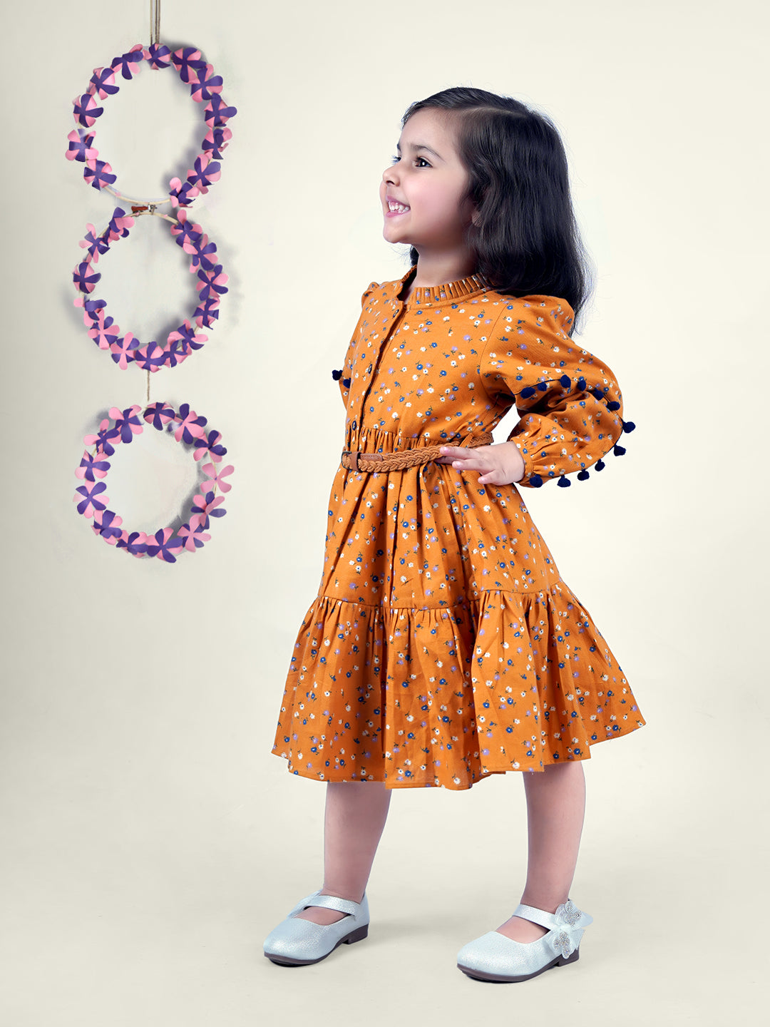 A girl wearing mustard color printed cotton frock with belt