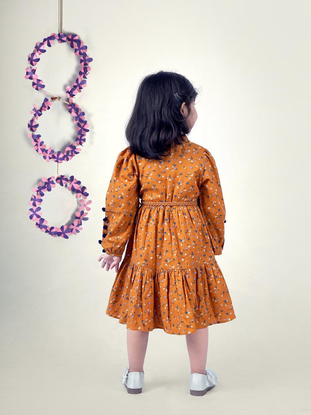 A girl wearing mustard color printed cotton frock with belt