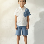Young boy wearing a white shirt with blue accents and blue shorts against a light background
